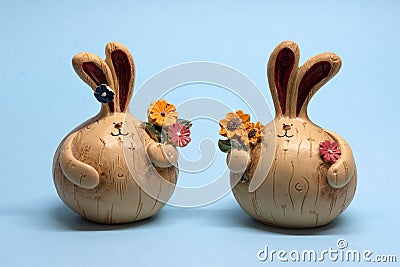 Small figures of two hares with flowers on a blue background Stock Photo