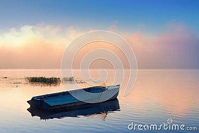 Small Fishing boat anchored near fog on river Stock Photo