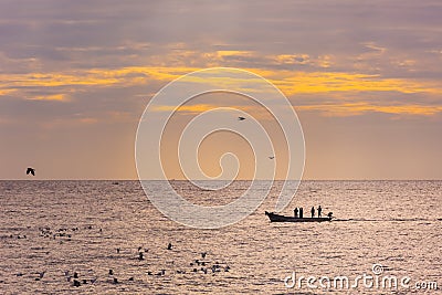 Small fishing boat with fishermen on the sea near Puducherry in South India during sunrise Stock Photo