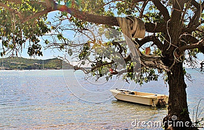 Small fishing boat floating on the ocean, with sailboats and mountains in the background Stock Photo