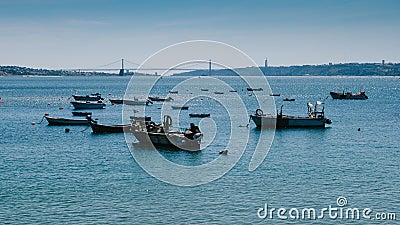 Small fishing boats on the Tagus overlooking the iconic 25 April Bridge, Lisbon, Portugal - Costa Verde Portuguese Editorial Stock Photo