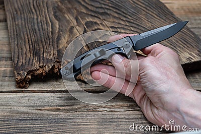 Small folding knife in hand. The blade and knife handle are black Stock Photo