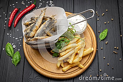 Small fried fish and french fries at an seaside restaurant. Fried anchovies Stock Photo