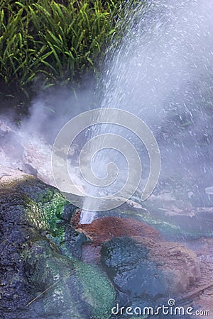 A small geyser erupts sending steam and water into the air Stock Photo