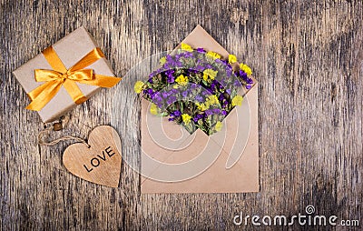 A small gift with a gold ribbon, an envelope with flowers and a heart. Romantic concept. Stock Photo