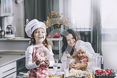 Small girl child eats a donut with my mom and sister happy cook Stock Photo