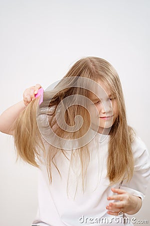 small girl combs long and tangled hair. white background. Stock Photo