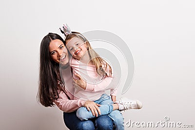 A small girl with crown headband and her mother sitting in a studio. Stock Photo