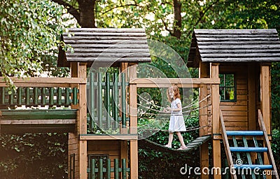 Small girl outdoors on wooden playground in garden in summer, playing. Stock Photo