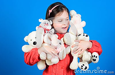 Small girl smiling face with toys. Happy childhood. Little girl play with soft toy teddy bear. Lot of toys in her hands Stock Photo