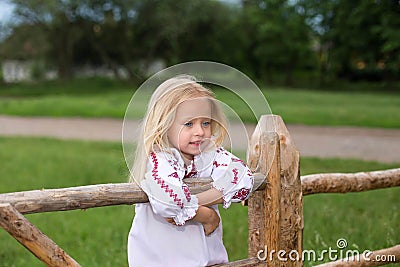Small girl in ukrainian traditional clothes on the hedge Stock Photo
