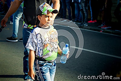 Small girl in variegated costume passes by city street at dominican annual carnival Editorial Stock Photo