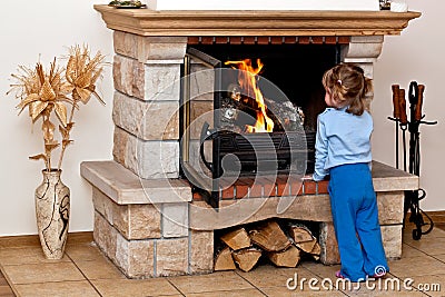 Small girl warms by the fireplace Stock Photo