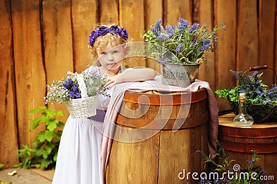 Small girl in white clothes and violet wreath in rustic style decorations. Ecolife. Organic and ecological lifestyle in childhood Stock Photo