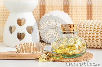 Small glass bottle with cosmetic oil serum, fish oil capsules and wooden hair brush. Natural spa, hair care and beauty treatment Stock Photo