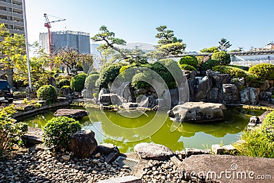 Small green pond next to Fukusai-ji buddhist temple in Nagasaki, with green water and traditional japanese garden trees, Japan. Stock Photo