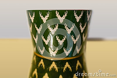 Small green porcelain bowl with red color inside and light pattern with mooses reflected in mirror Stock Photo