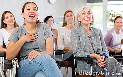 small group of women are sitting in audience, listening to lecture and laugh at amusing case Stock Photo