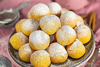 Small homemade curd donuts with icing sugar on a gray concrete background with a pink napkin. Close-up Stock Photo