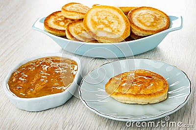 Small pancakes in blue plate, lemon jam in bowl, pancake with lemon jam in saucer on wooden table Stock Photo