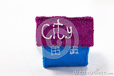 A small house of blue color and a purple roof stands on a white surface. Stock Photo