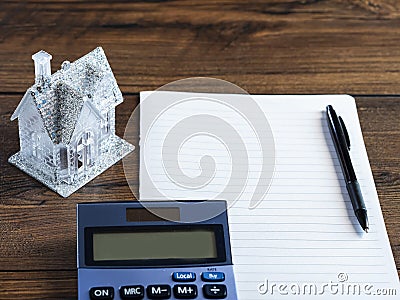 Small house with glitter on a piece of blank paper and wooden table and calculator. Buying dreamy glamourous home. Planning Stock Photo