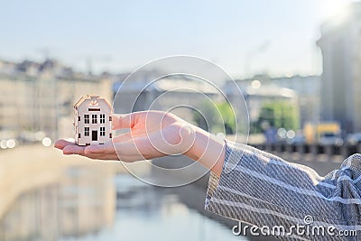 Small house on hand against the background of the city, real estate agent concept, developers, preferential mortgages Stock Photo