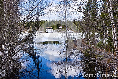 Small houses in the snowy forest overlooking the frozen lake Stock Photo
