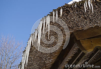 Small icicles retro straw roof background blue sky Stock Photo