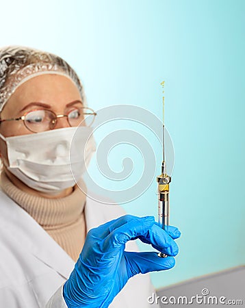 A small injection syringe in the doctor s hand in a latex medical glove and a face mask. Virus protection concept. Medical theme Stock Photo