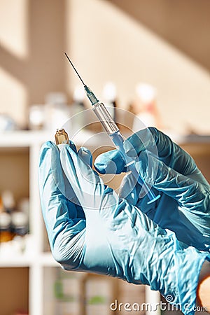 Small injection! Vet`s hands in protective gloves holding a syringe and vaccine in veterinary clinic. Close-up. Stock Photo