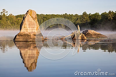 Unique Boulders Reflected In The Calm Early Morning Water Stock Photo