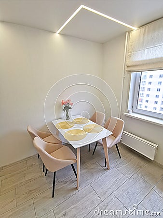 Small kitchen corner with white walls, a dining table and beige armchairs. Stock Photo