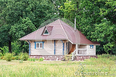 A small log house with a triangular roof in front of forest Stock Photo