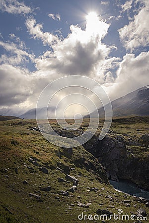 Small lonely hiker standing in enormous cloud and sunlight covered autumn wilderness Stock Photo