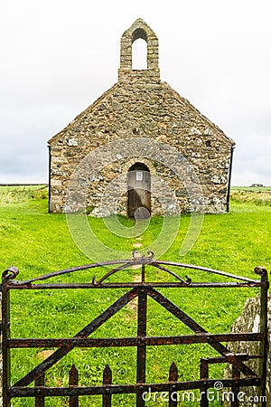 Small medieval Welsh Chapel in field, Anglesey. Gate in foreground Stock Photo