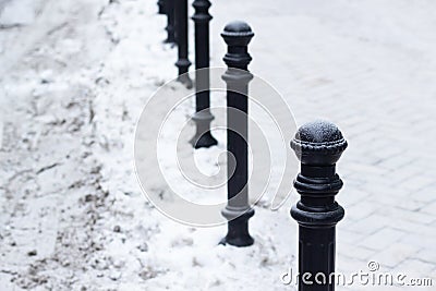 Small metal column pillar banister. Snow in street. Winter outdoor Stock Photo
