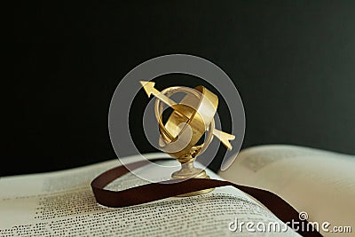 Small miniature astrolabe globe on an open book. Stock Photo