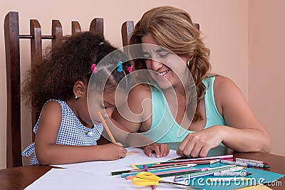 Small multiracial girl and her mother drawing with color pencils Stock Photo