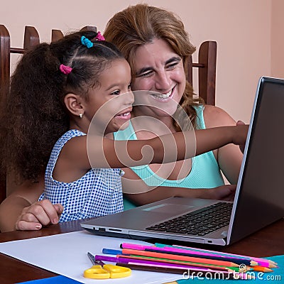 Small multiracial girl and her mother working on a laptop comput Stock Photo