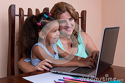 Small multiracial girl and her mother working on a laptop comput Stock Photo