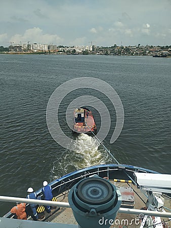 Small and old tugboat towing a large vessel to a port to offload cargo Stock Photo
