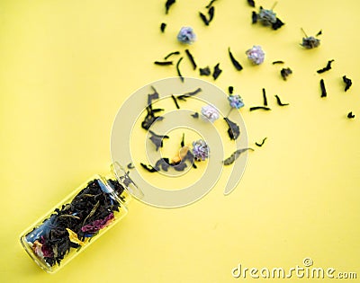 Small old vintage glass bottle with defocused floral tea and blue and pink petals inside and scattered tea petals and flowers on Stock Photo