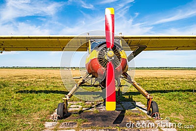 Small old yellow and red plane standing in summer field front view Stock Photo