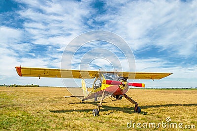 Small old yellow and red plane standing in summer field front view Stock Photo