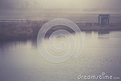 A small outbuilding on a pond on a foggy afternoon Stock Photo