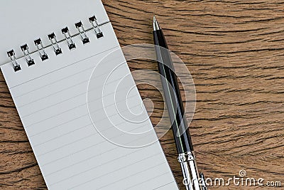 Small paper notepad with blank page, pen on wooden table using as meeting note, writing message or task list on working project Stock Photo