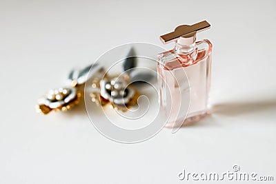 Small parfume bottle and golden earrings on white background. Stock Photo