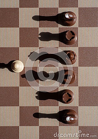 Small pawn on chess board outnumbered against larger adversary concept of adversity ,discimination ,equality Stock Photo