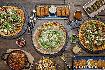 Small pizzas with lots of arugula, lasagna with tomato, sarma on a pink plate, croquettes and rolls. Cardamom, pepper and potatoes Stock Photo